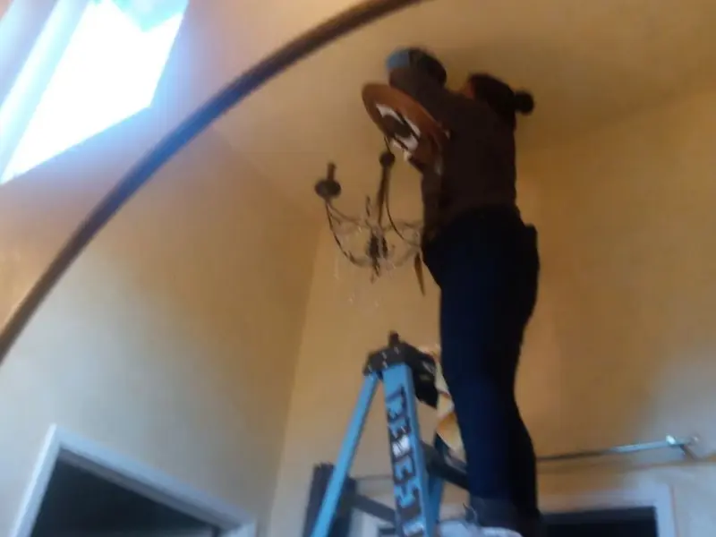 Electrician installing a chandelier in a Park City residence